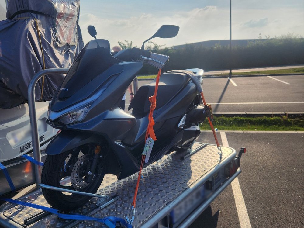 Honda PCX scooter on trailer being towed by motorhome